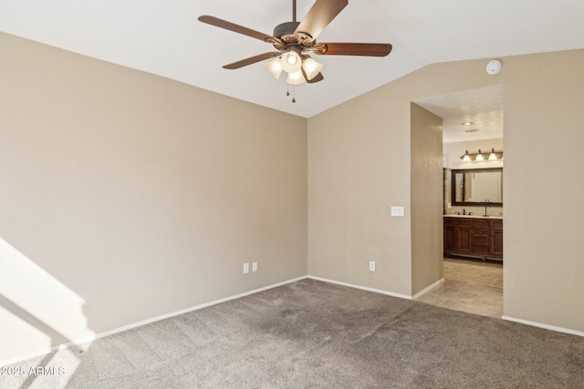 carpeted empty room with sink, vaulted ceiling, and ceiling fan