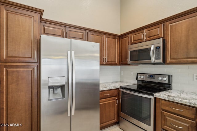 kitchen with light stone counters, appliances with stainless steel finishes, and tasteful backsplash