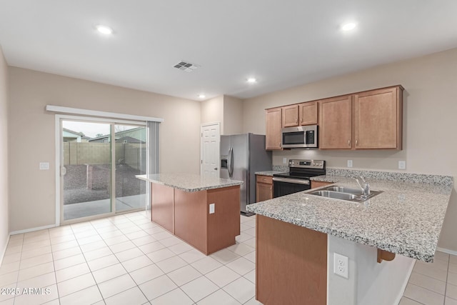 kitchen featuring light stone counters, sink, stainless steel appliances, and a center island