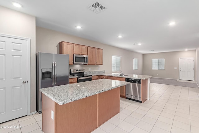 kitchen with light tile patterned floors, sink, appliances with stainless steel finishes, light stone countertops, and kitchen peninsula