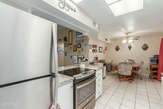 kitchen featuring electric stove, light tile patterned floors, refrigerator, light stone countertops, and white cabinets