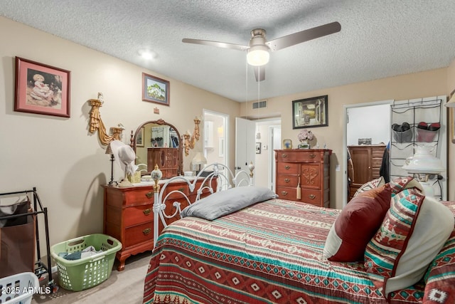 carpeted bedroom featuring ceiling fan and a textured ceiling