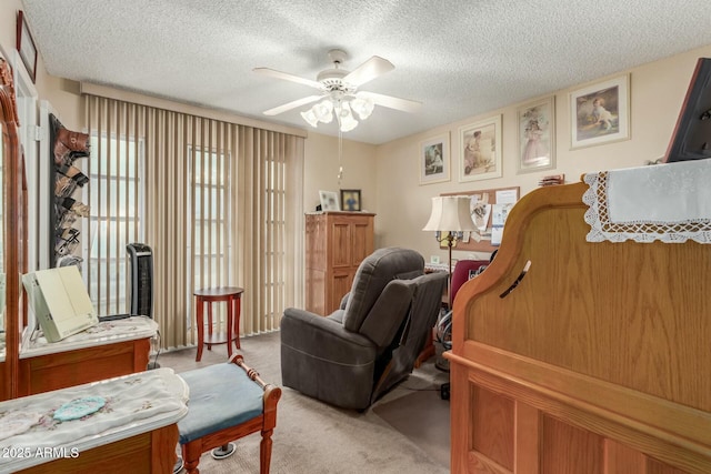 sitting room featuring ceiling fan, carpet, and a textured ceiling