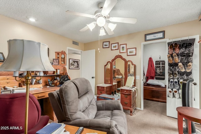 carpeted living room featuring ceiling fan and a textured ceiling