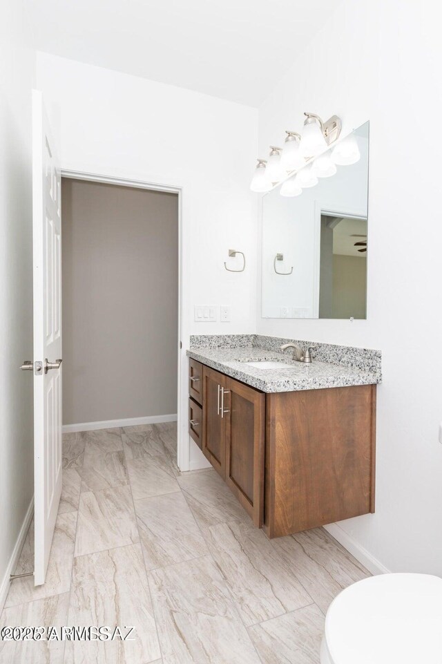 19 E Elm St, Tucson, AZ 85705 - bathroom featuring vanity, marble look tiles, baseboards, and toilet