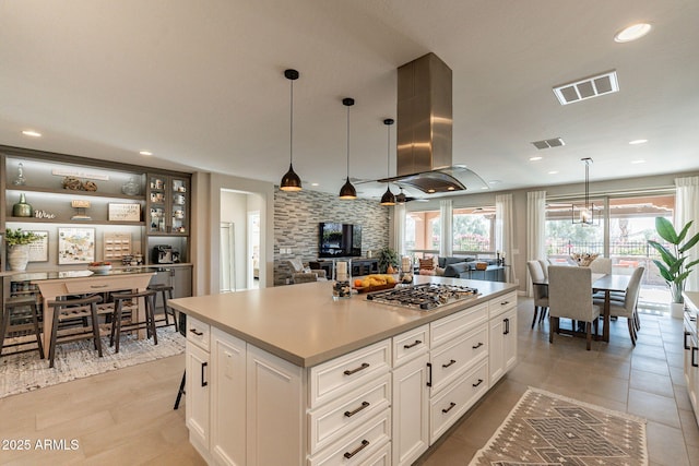 kitchen with white cabinetry, island range hood, hanging light fixtures, a kitchen island, and stainless steel gas stovetop