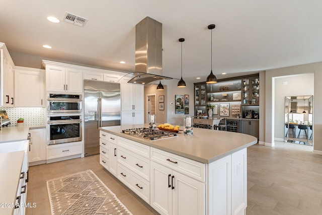 kitchen with pendant lighting, appliances with stainless steel finishes, white cabinetry, a center island, and island exhaust hood