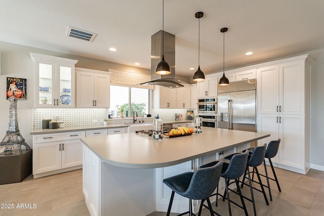 kitchen featuring island exhaust hood, stainless steel appliances, a kitchen island with sink, and white cabinets