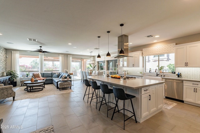 kitchen with stainless steel dishwasher, a center island with sink, and white cabinets