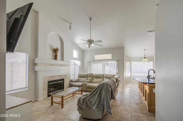 living area featuring ceiling fan, a tiled fireplace, and a healthy amount of sunlight