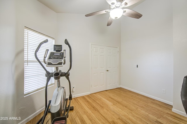 exercise area featuring baseboards, a ceiling fan, and light wood-style flooring