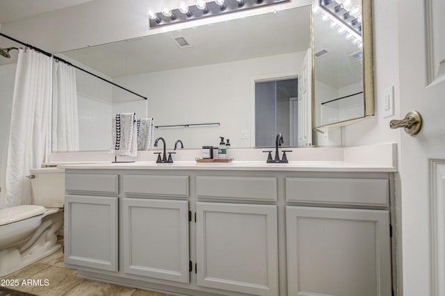 full bath featuring visible vents, double vanity, a sink, and toilet