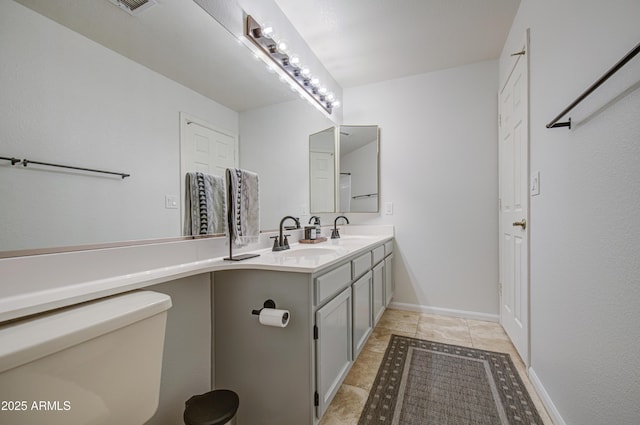 bathroom featuring double vanity, toilet, a sink, and tile patterned flooring