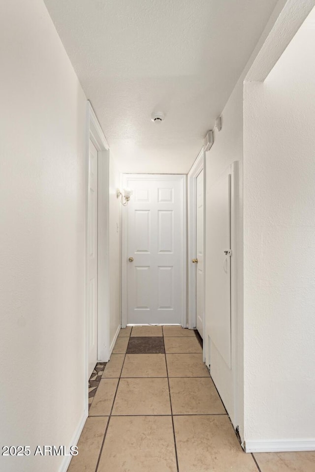 hall featuring a textured ceiling and light tile patterned floors