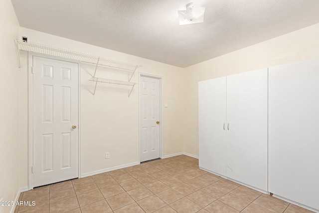 unfurnished bedroom featuring a closet, a textured ceiling, and light tile patterned flooring