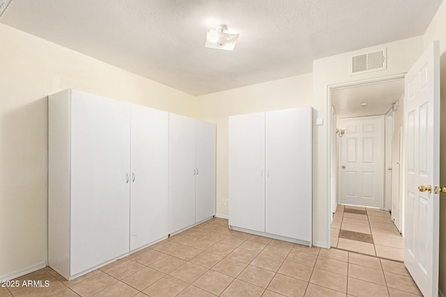 unfurnished bedroom with a closet, a textured ceiling, and light tile patterned floors