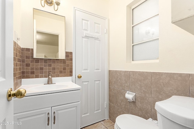 bathroom featuring vanity, toilet, tile patterned flooring, and tile walls