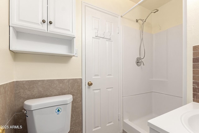 bathroom featuring tile walls, toilet, and walk in shower