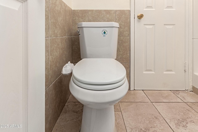 bathroom with tile patterned flooring, tile walls, and toilet