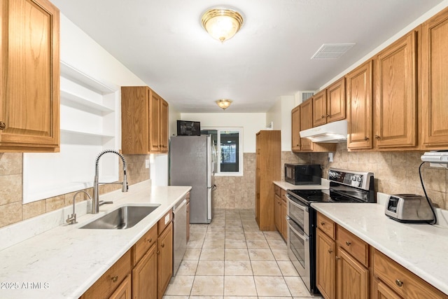 kitchen featuring sink, light tile patterned floors, appliances with stainless steel finishes, backsplash, and light stone counters