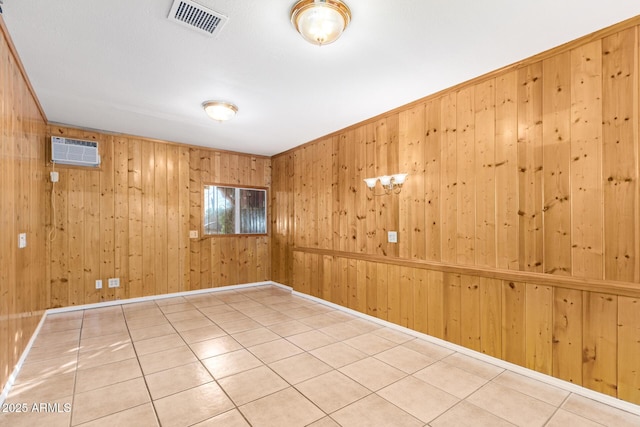 spare room featuring tile patterned flooring, wooden walls, and an AC wall unit