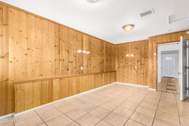 unfurnished room featuring light tile patterned floors and wooden walls