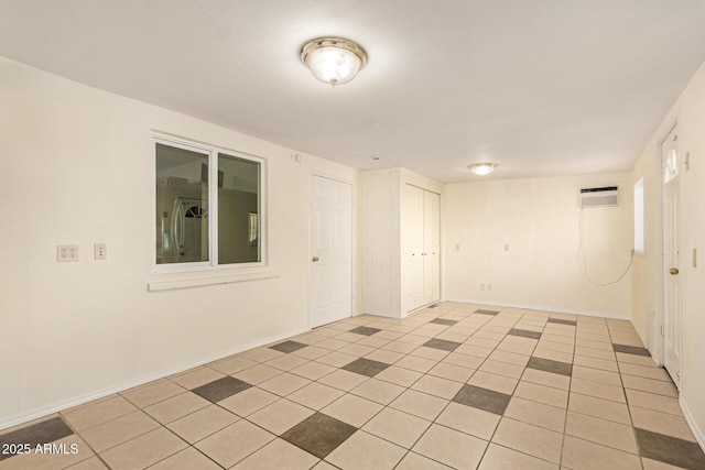 unfurnished room with an AC wall unit and light tile patterned floors