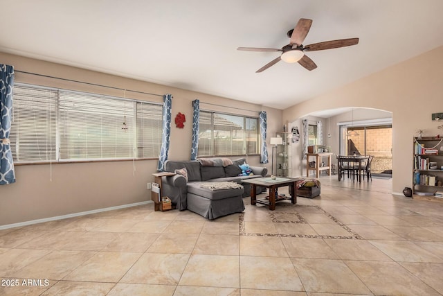 living room with light tile patterned floors, baseboards, arched walkways, lofted ceiling, and ceiling fan