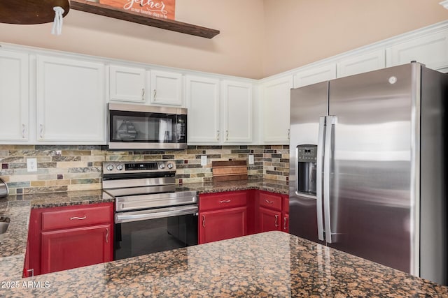 kitchen with stainless steel appliances, white cabinets, dark stone countertops, and tasteful backsplash