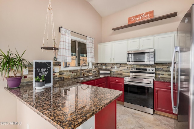 kitchen featuring a peninsula, appliances with stainless steel finishes, decorative backsplash, and a sink