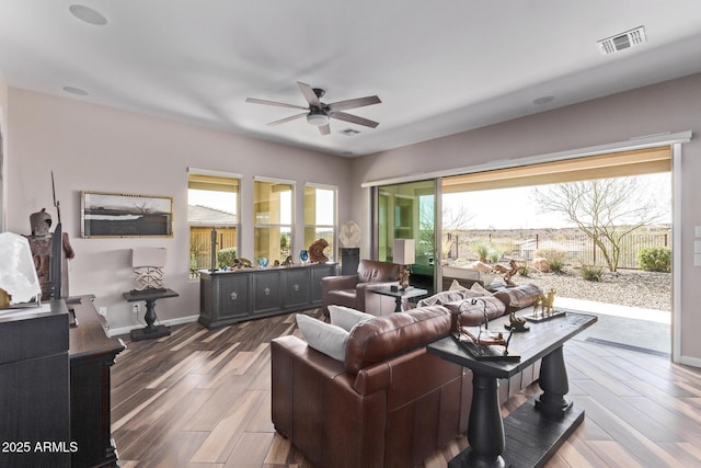 living area with visible vents, baseboards, ceiling fan, and wood finished floors