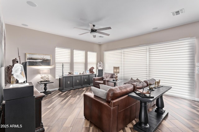 living room with visible vents, baseboards, light wood-type flooring, and a ceiling fan