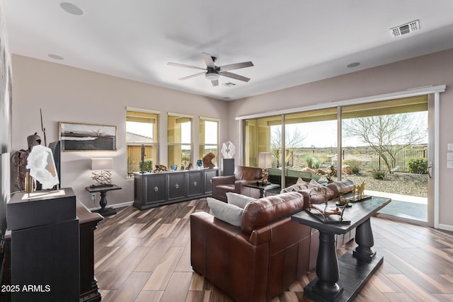 living room featuring visible vents, baseboards, ceiling fan, and wood finished floors