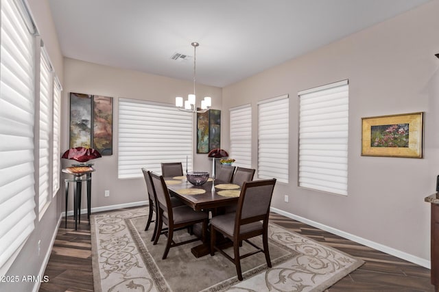 dining area with visible vents, wood finished floors, baseboards, and a chandelier