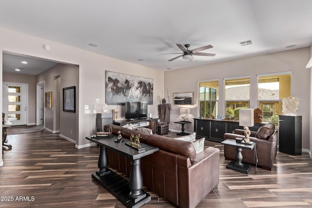 living room with dark wood-style floors, visible vents, a ceiling fan, and baseboards