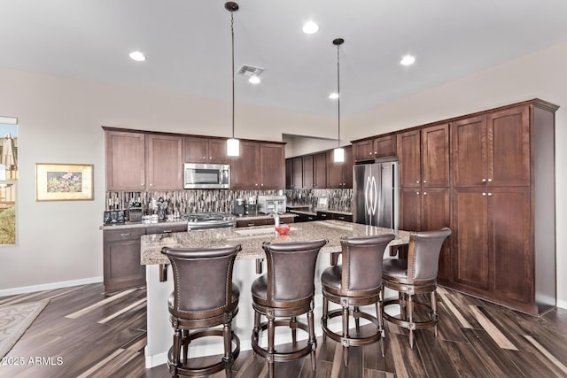 kitchen with tasteful backsplash, appliances with stainless steel finishes, dark wood-type flooring, and a kitchen island with sink