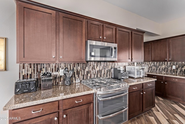 kitchen with tasteful backsplash, stainless steel appliances, light stone counters, and wood finished floors