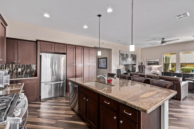 kitchen with visible vents, dark wood-type flooring, light stone counters, appliances with stainless steel finishes, and a sink