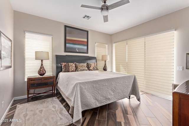 bedroom with visible vents, a ceiling fan, baseboards, and wood finished floors