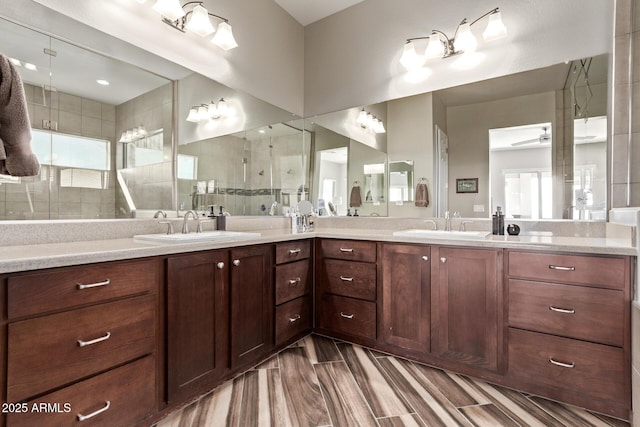 full bath with a sink, double vanity, plenty of natural light, and tiled shower