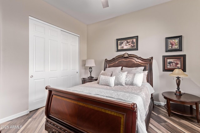 bedroom featuring ceiling fan, a closet, baseboards, and wood finished floors