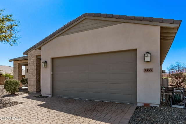 garage featuring decorative driveway and fence