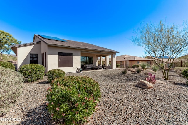 back of house featuring an outdoor living space, stucco siding, solar panels, and a patio area