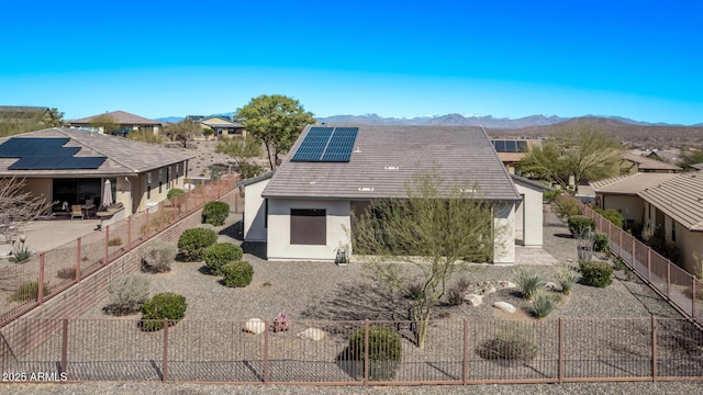 rear view of property featuring solar panels, a fenced backyard, stucco siding, a patio area, and a mountain view