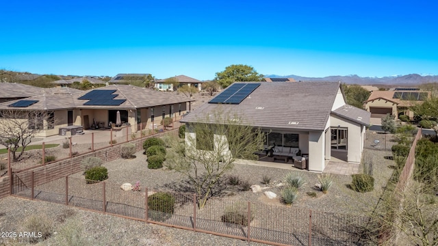 rear view of property with stucco siding, an outdoor living space, a fenced backyard, solar panels, and a patio area