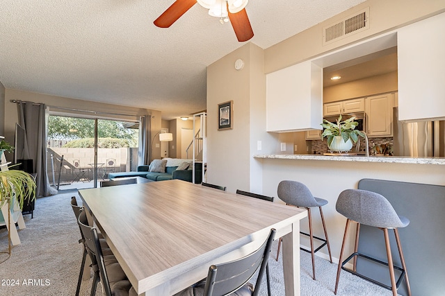 dining area with light carpet, a textured ceiling, and ceiling fan