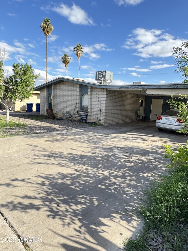 view of front of house featuring a carport, concrete driveway, and brick siding