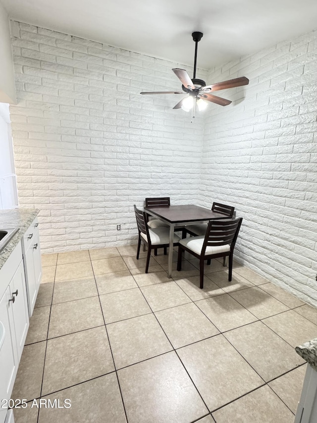 dining space featuring a ceiling fan, light tile patterned flooring, and brick wall