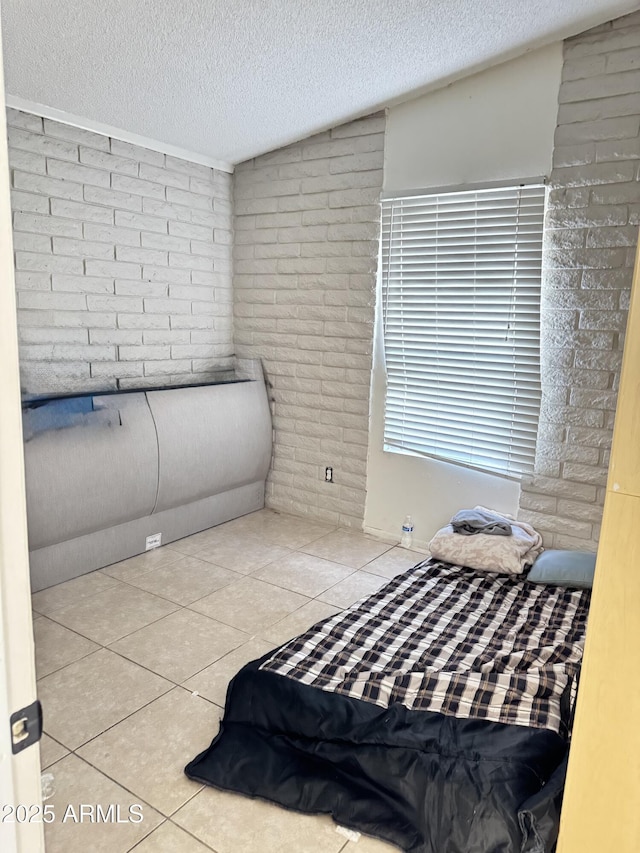 tiled bedroom with a textured ceiling and brick wall