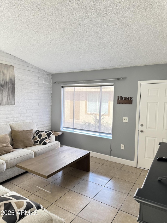 living area with brick wall, baseboards, lofted ceiling, light tile patterned flooring, and a textured ceiling